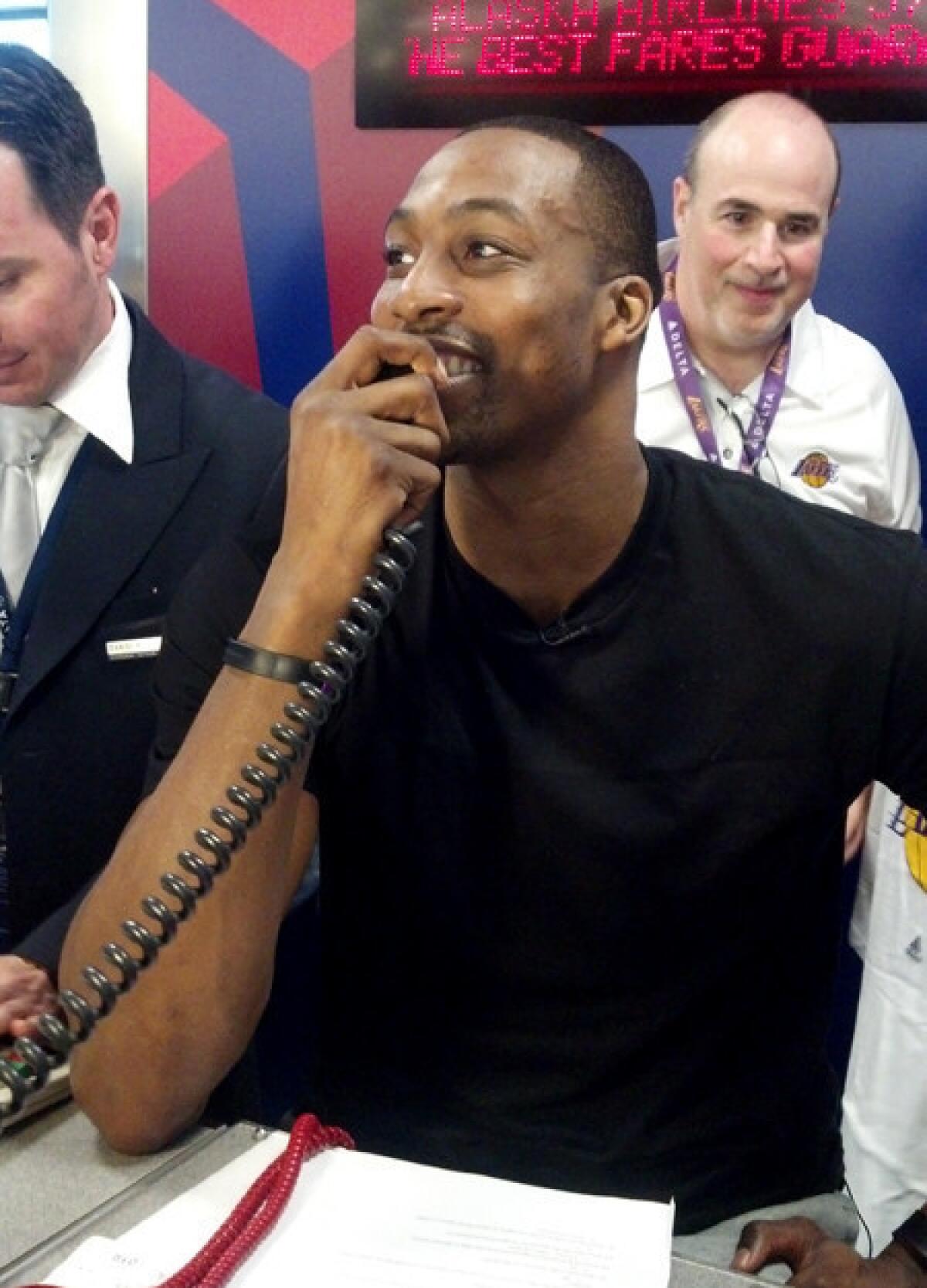 Lakers center Dwight Howard makes boarding announcements at a Delta Air Lines counter before Flight 1553 to Honolulu on Thursday.