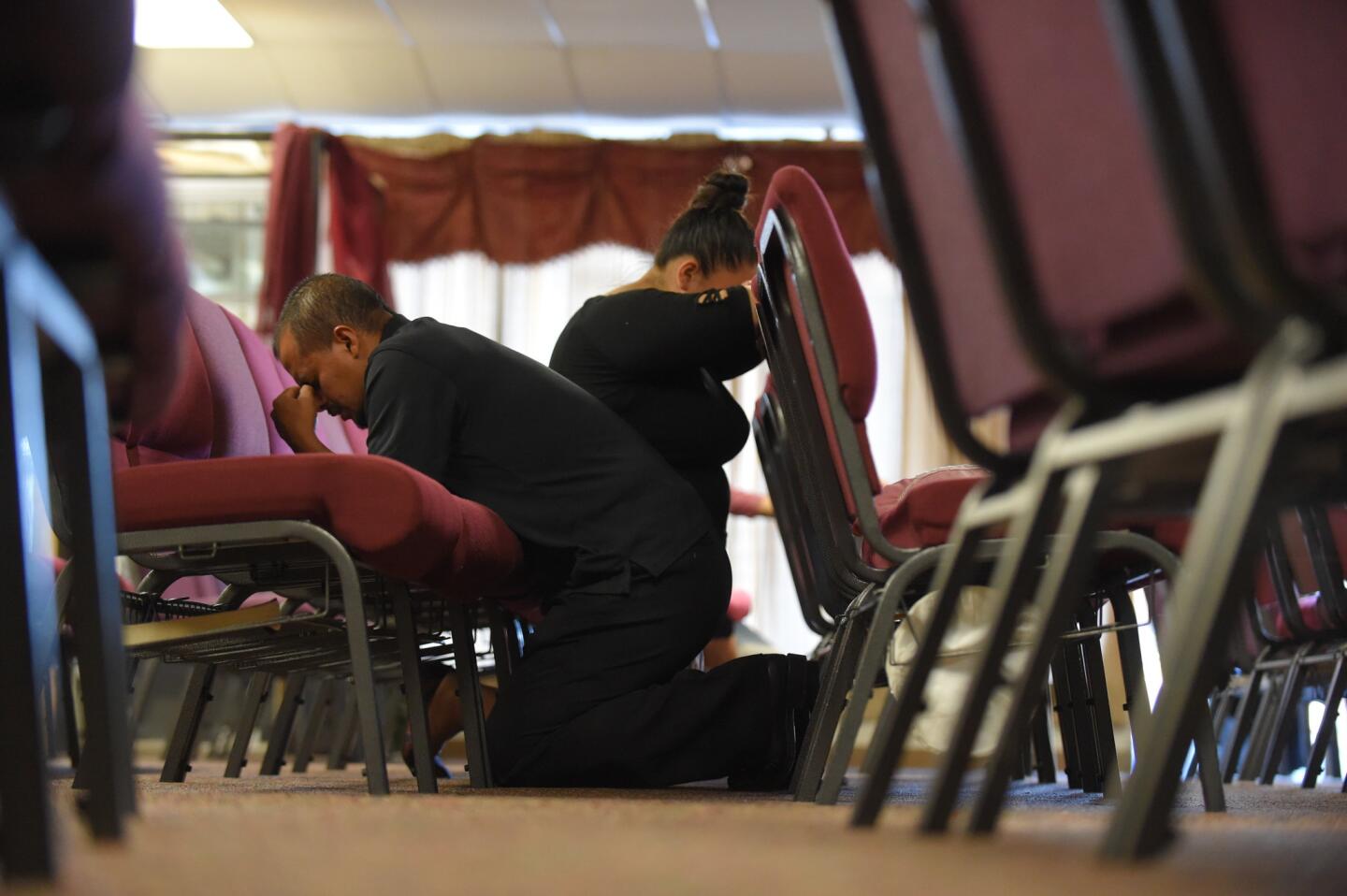From left, Alvin Lobo and Celena Rivera kneel during a family meeting for Jose Oscar Hidalgo Romero, one of the three people killed in Wednesday's attack in Edgewood. The service was held at The Church of Pentecostal Inc. in Aberdeen.