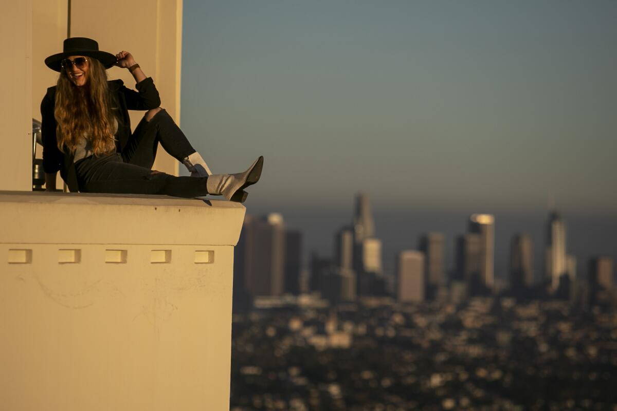 Karissa Green, 30, of Dallas, strikes a pose on the ledge of the Griffith Park Observatory as the sun sets.