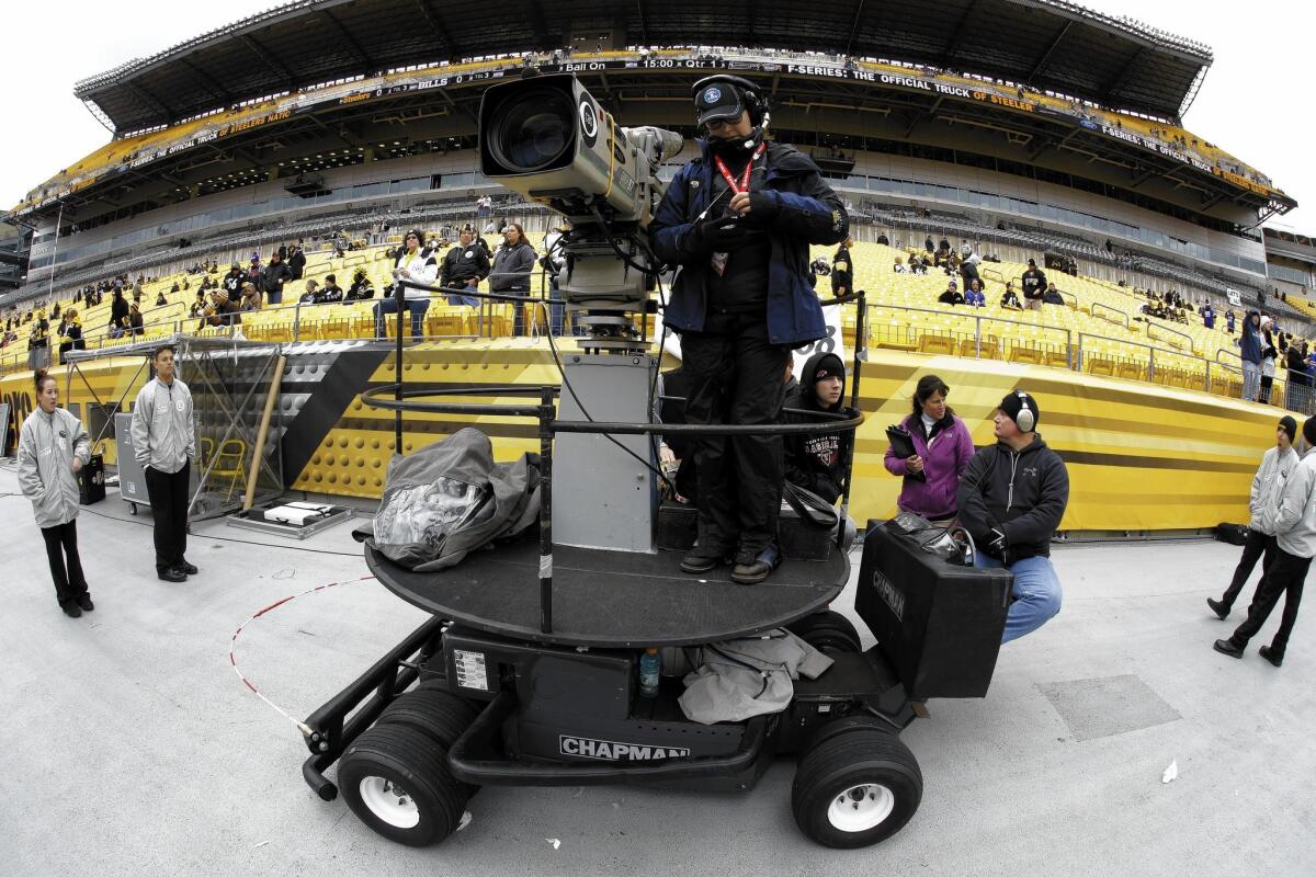 A CBS sideline camera operator prepares for an NFL football game between the Pittsburgh Steelers and the Buffalo Bills in Pittsburgh.