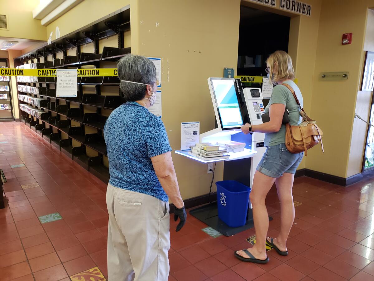 La Jolla/Riford Library patron Amanda Notman gets help from a librarian in using the self-checkout kiosk Oct. 5.