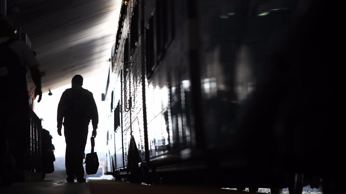 A commuter walks the Metrolink platform at Union Station, where a passenger was pronounced dead after a heart attack on a train coming from Orange County.