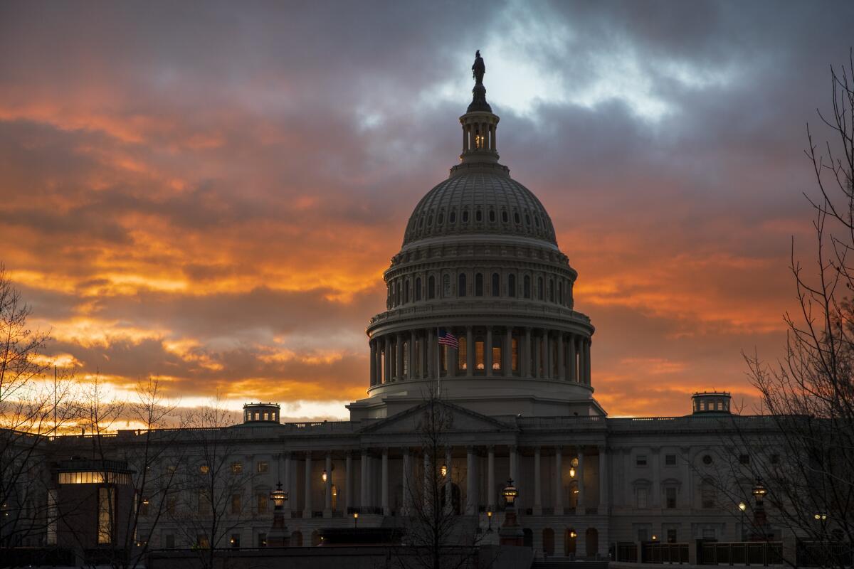 The U.S. Capitol in shadow with a dramatic red sunset behind it. 