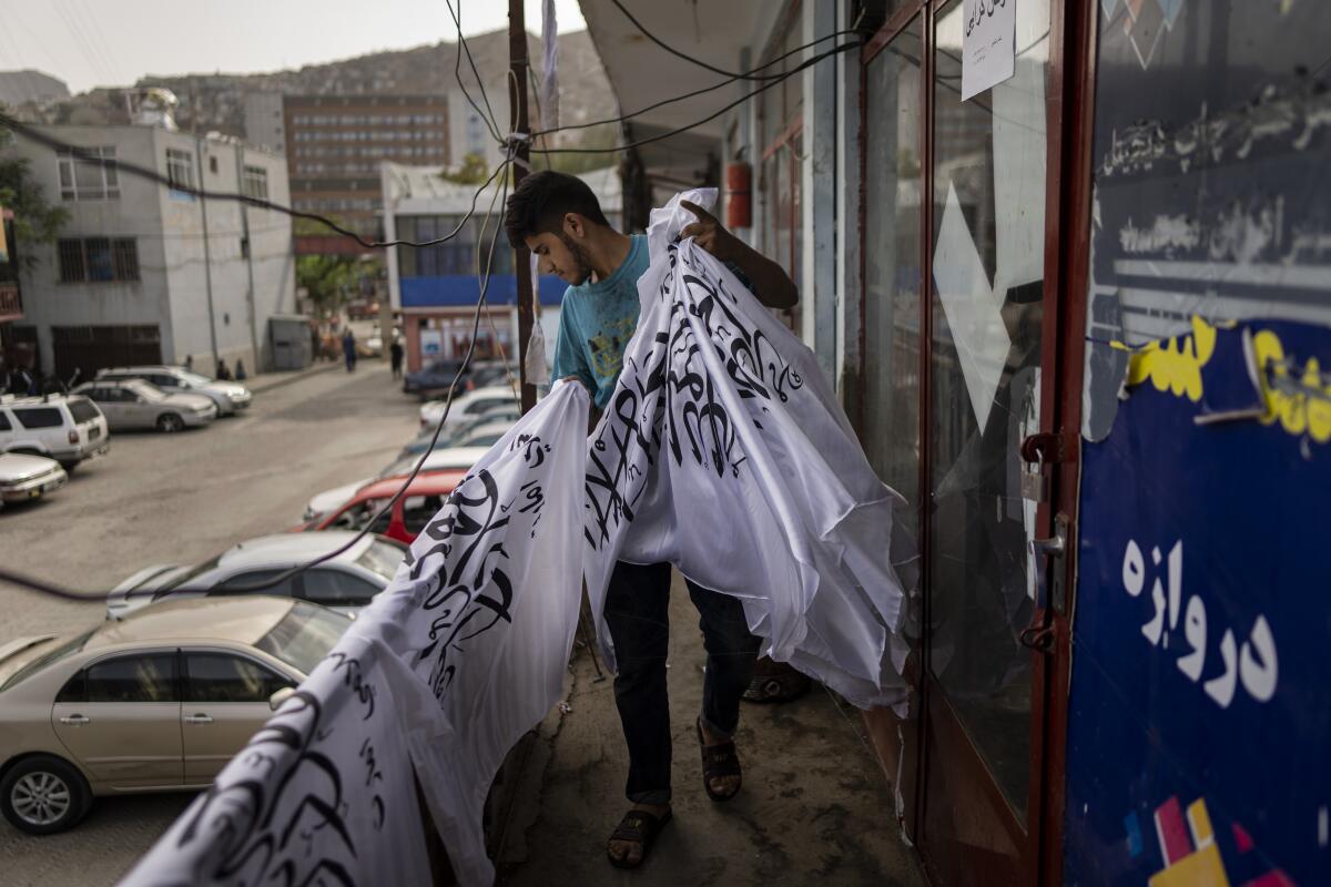 Worker collecting newly hand-printed Taliban flags