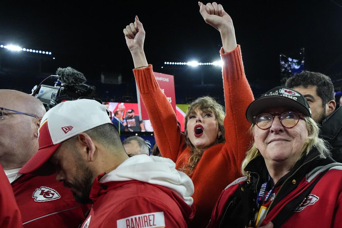 Taylor Swift raises her arms in a crowd of Chiefs fans