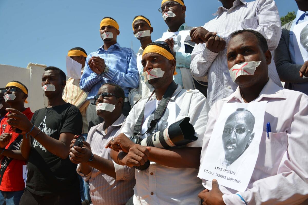 Somali journalists hold up the picture of arrested journalist Abdiaziz Abdinur Ibrahim at an event condemning his detention Sunday in Mogadishu.