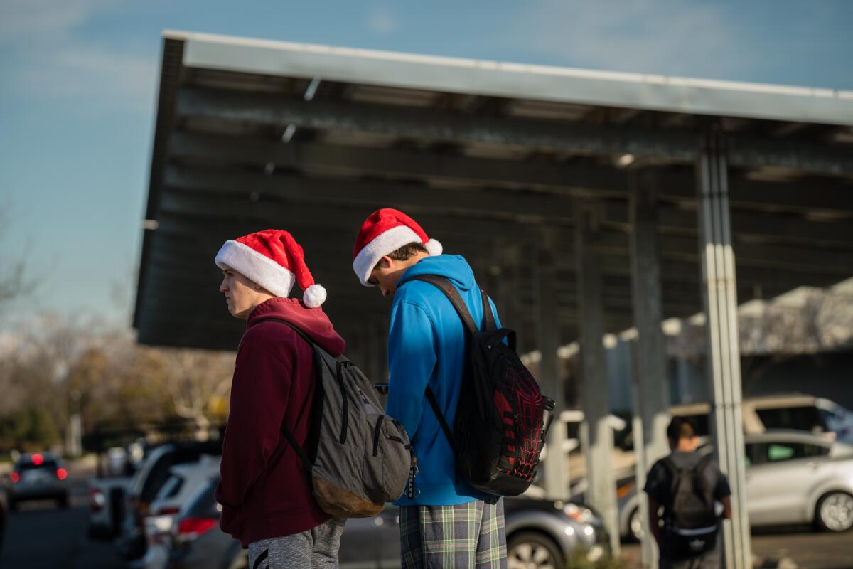 Students stand near a parking lot covered with a metal structure