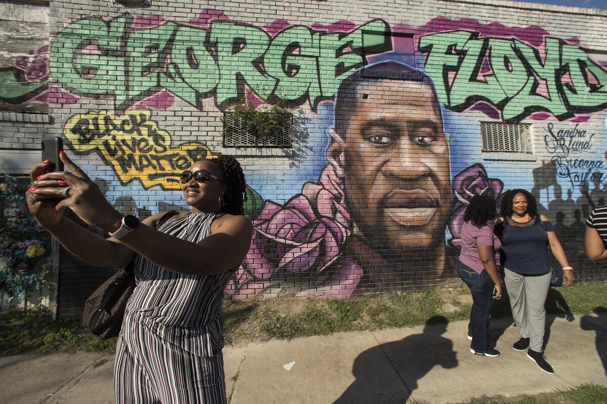 FILE - In this Tuesday, April 20, 2021, file photo, Laynette Jacob takes a photo in front of a George Floyd mural with her friends near the intersection of Elgin and Ennis as she joins others as they react after learning of the guilty verdict on all counts in the murder trial of former Minneapolis police Officer Derek Chauvin in the death of George Floyd, in Houston. In an announcement Monday, Oct. 4, 2021, a Texas agency has approved a request that Floyd be granted a posthumous pardon for a 2004 drug arrest made by a now indicted ex-Houston police officer whose case history is under scrutiny following a deadly drug raid. (Brett Coomer/Houston Chronicle via AP, File)
