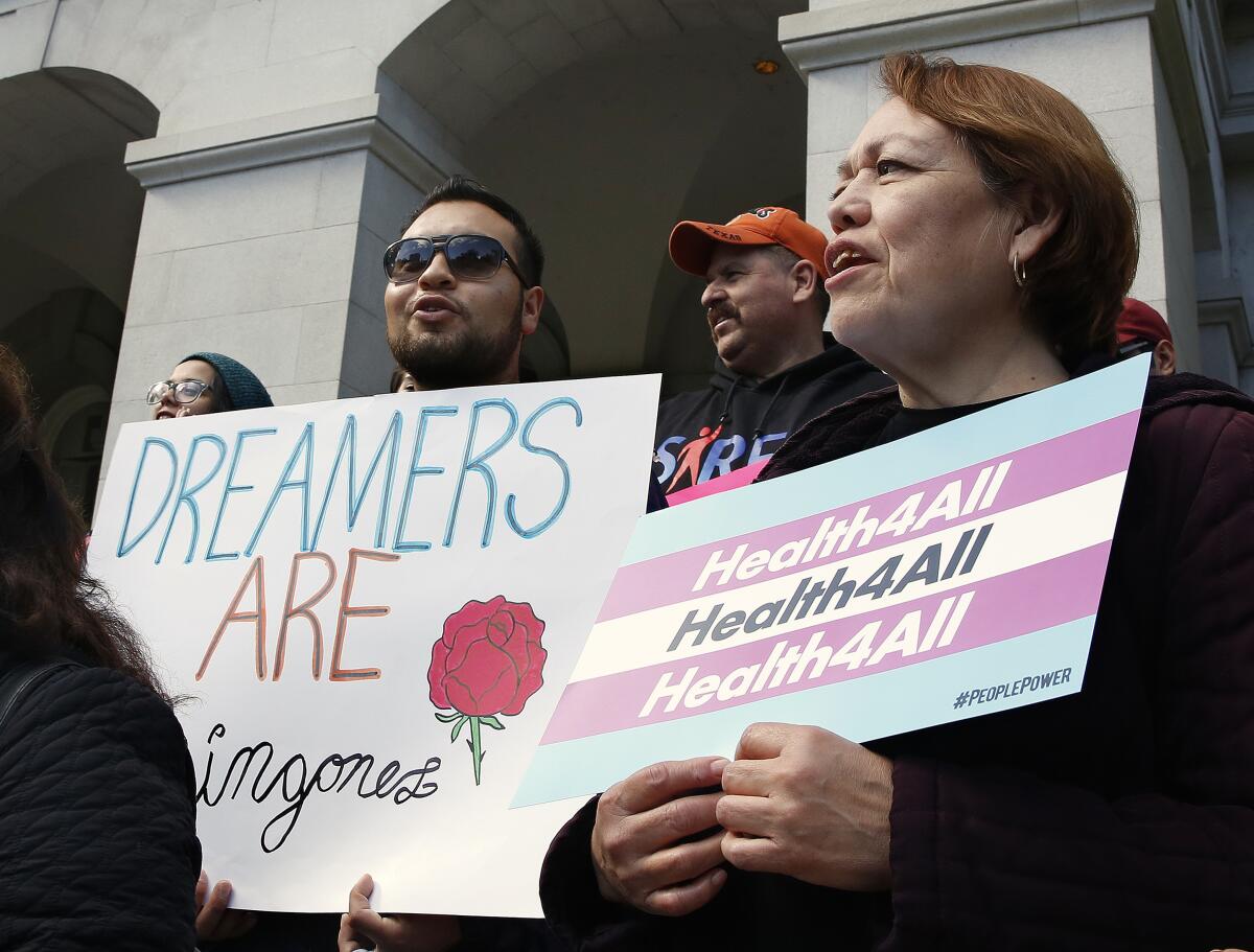 Protesters stand in front of a building holding signs