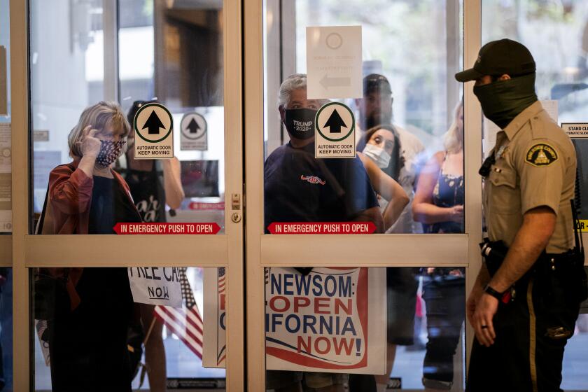 RIVERSIDE, CALIFORNIA - MAY 8, 2020: Residents who want public health orders rescinded wait to enter the County Adminstrative Center to speak during the public comment time of an emergency Riverside County Board of Supervisors meeting in the midst of the ongoing coronavirus pandemic on May 8, 2020 in Riverside, California. (Gina Ferazzi/Los Angeles Times)