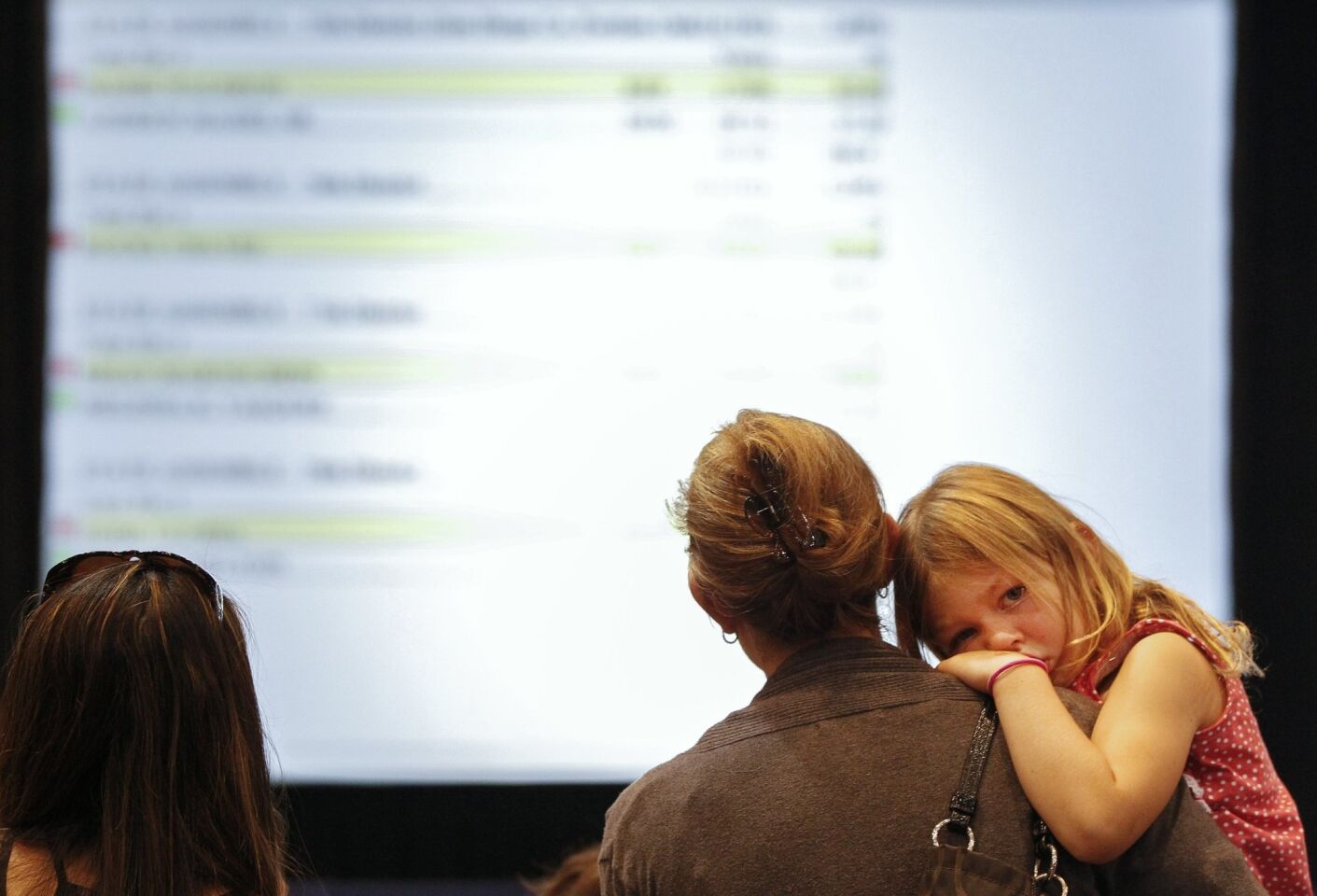 Four-year-old Myla Garcia rest her head on her mother Brooke Garcia's shoulder as she looks for assembly candidate Todd Gloria's results, who Garcia is a supporter of, on a screen at Golden Hall.