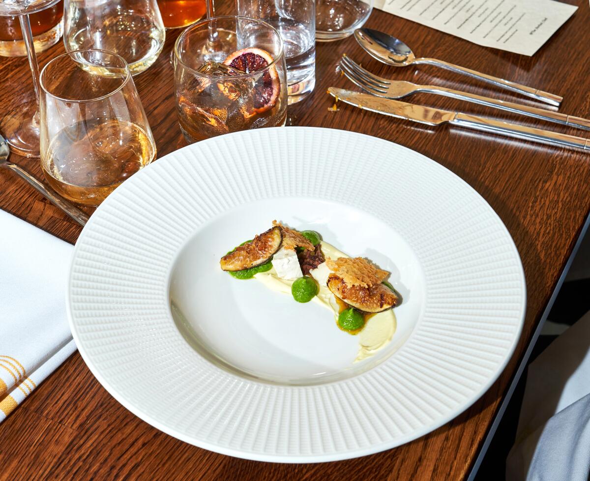 A dinner plate containing a dainty portion of goat's milk cheese, dabs of green sauce and figs.