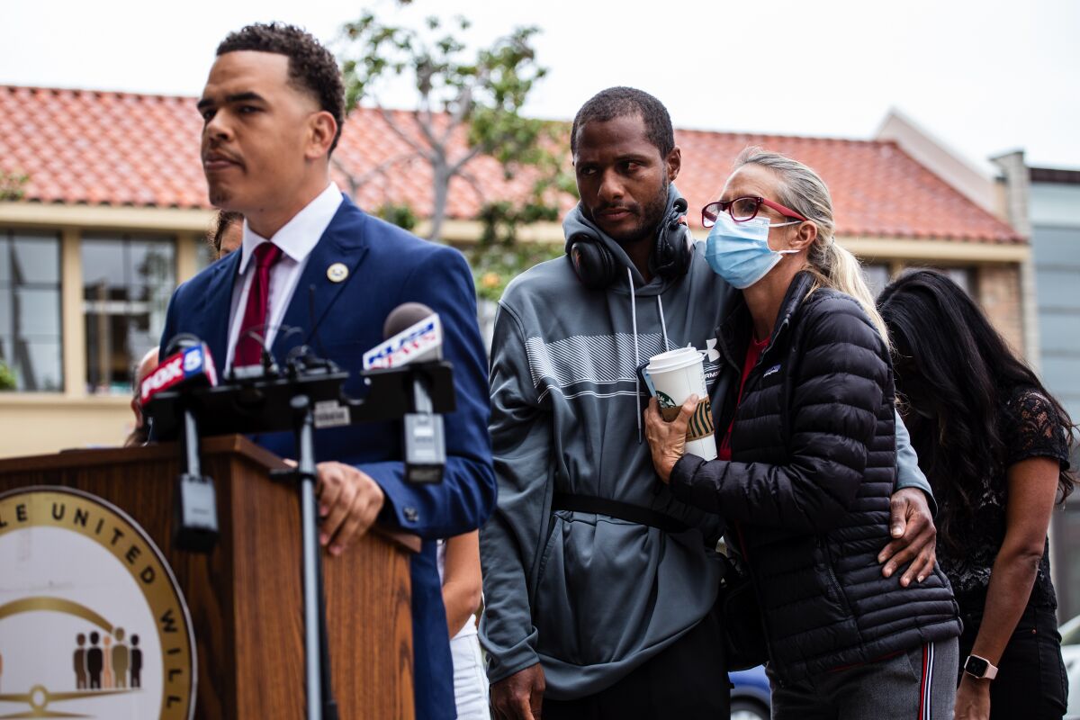 Jesse Evans and community member Amie Zamudio embrace as civil-rights activist Shane Harris speaks in La Jolla.