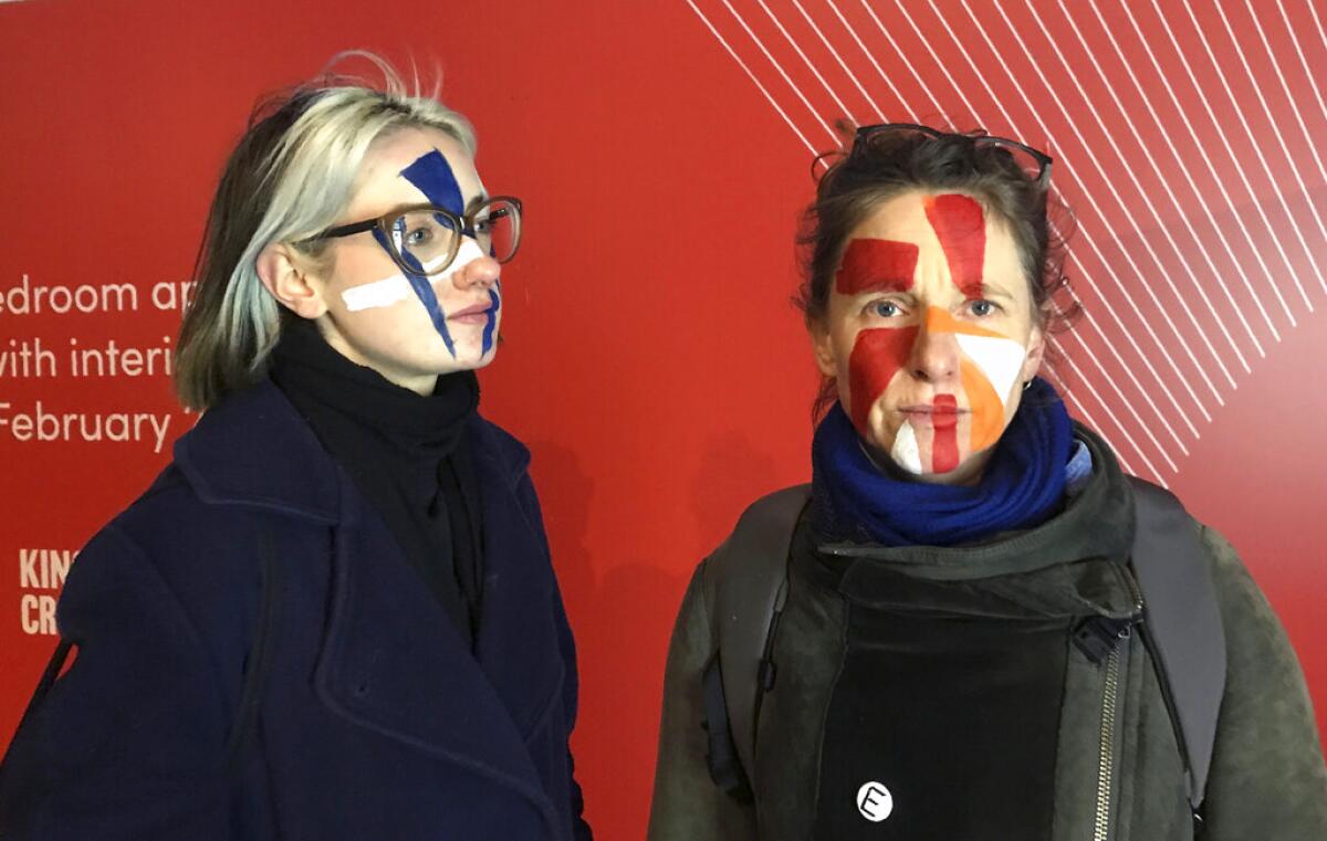 En esta imagen tomada el 17 de febrero de 2020, las artistas Georgina Rowlands, a la izquierda, y Anna Hart, a la derecha posan para una foto con el rostro pintado para eludir a los sistemas de reconocimiento facial. (AP Foto/Kelvin Chan)