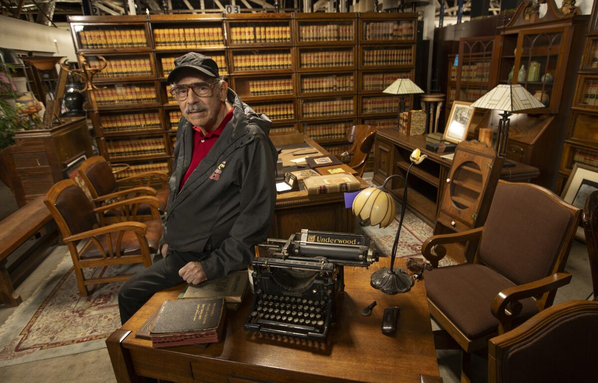 A man sits at a desk with a typewriter and books.