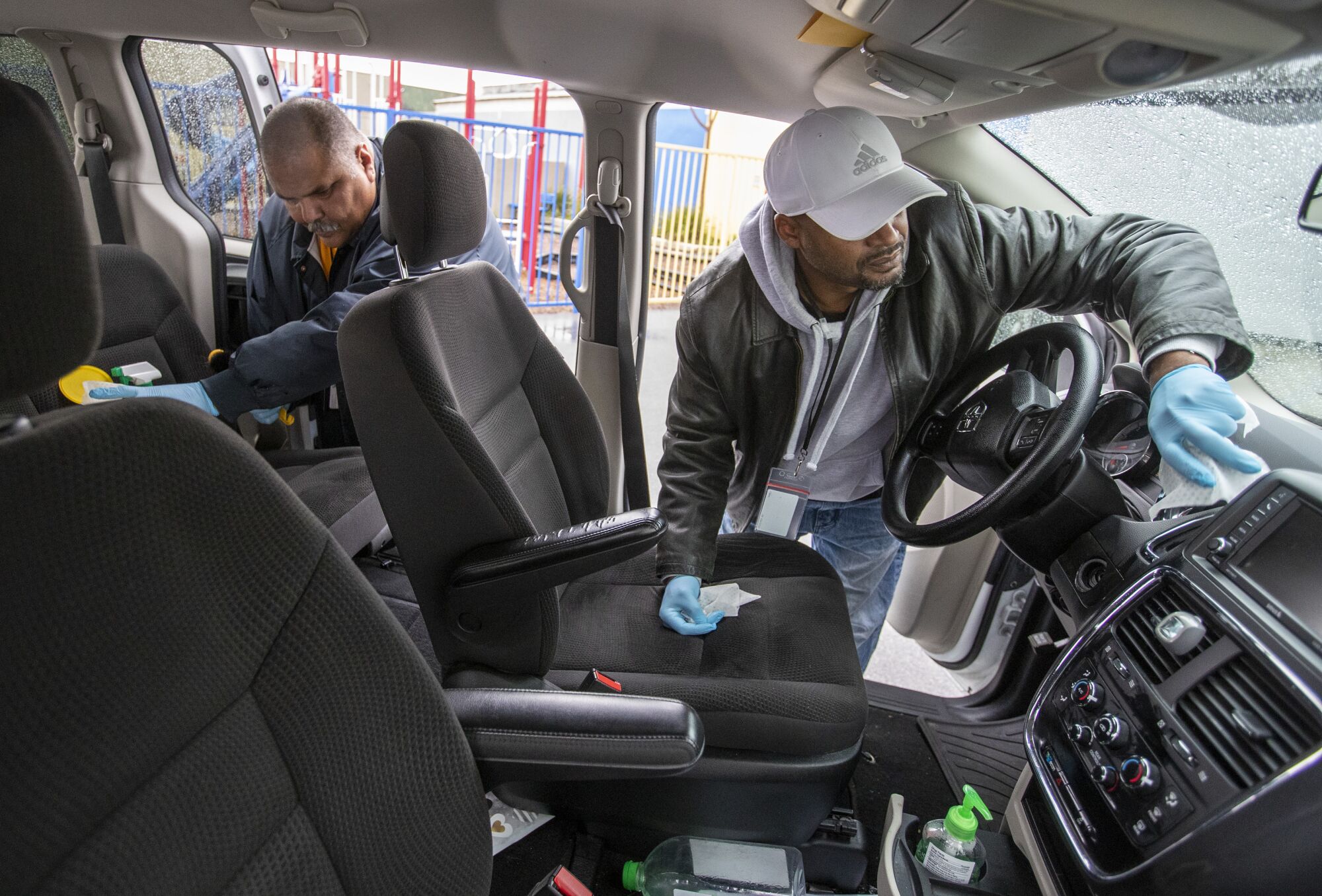 Outreach workers Ralph Gomez, left, and Kenya Smith sanitize their van before going out to look for homeless people as part of their program in Los Angeles.