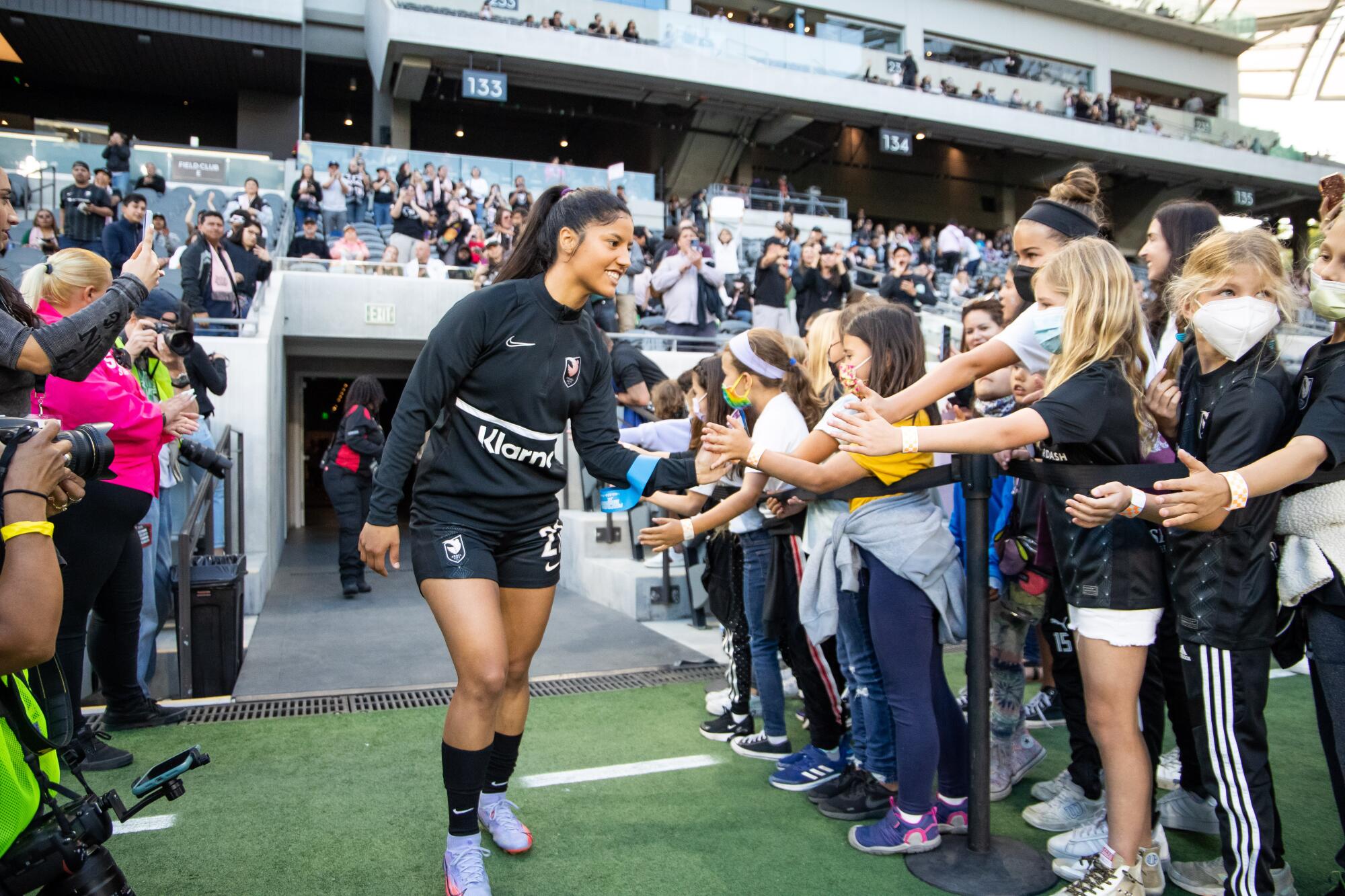 Angel City FC's Stefany Ferrer Van Ginkel greets fans while walking out to the field before a game.