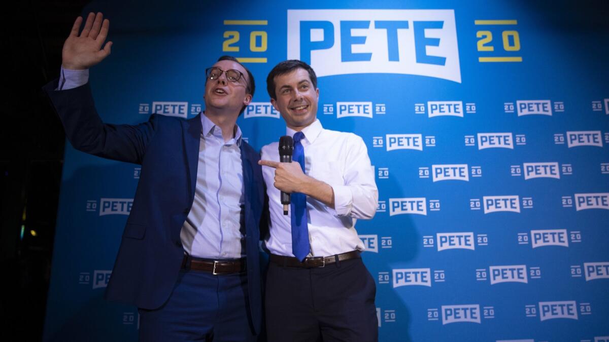 Democratic presidential candidate Pete Buttigieg, right, and husband, Chasten, acknowledge supporters after speaking at a campaign event.