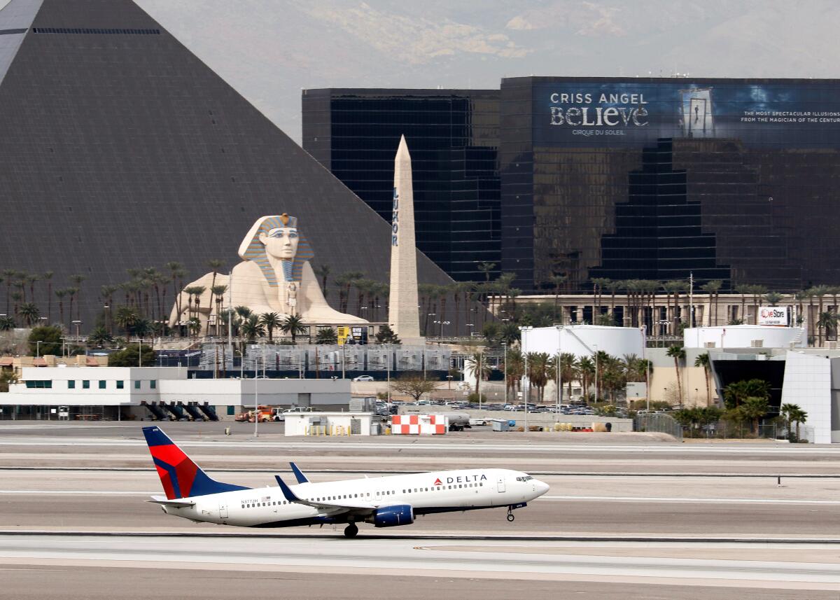 A Delta Airlines jet on a runway with the Luxor Hotel and Casino seen in the background.