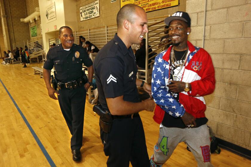 Eric Romero, 30, right, a resident at the Imperial Courts Housing Development in Watts, chats with Los Angeles police officers Delano Hutchins, left, and Angelo Marzan on July 30, 2015. The officers are members of the LAPD's Community Safety Partnership program.