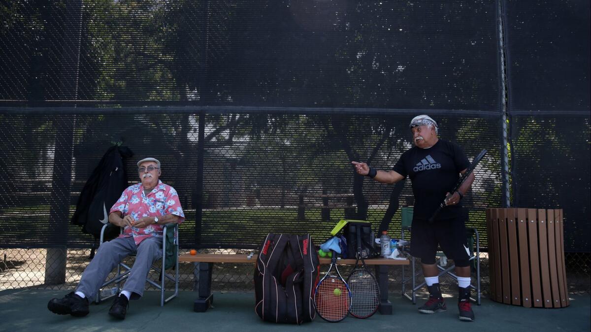 Milo Gutierrez, left, jokes with Rocky Garcia, right, a retired union representative, while playing tennis.