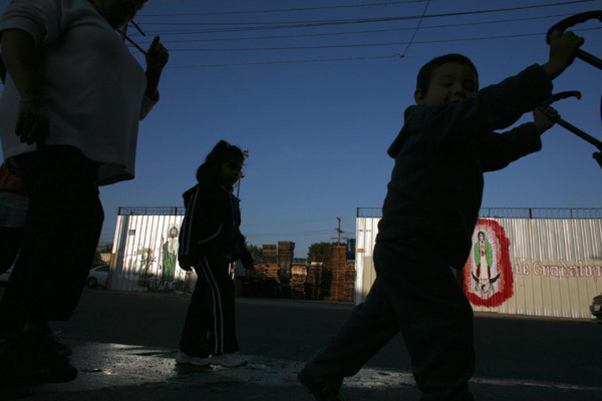 Children walk down a stretch of East 29th Street in South Los Angeles. Los Angeles officials are in the final stages of negotiating a complex settlement that would relocate a metal finishing plant that has been the bane of a poor neighborhood, replacing a stretch of blocks that are gritty even by the standards of South L.A. with a large affordable-housing project.. More photos >>>