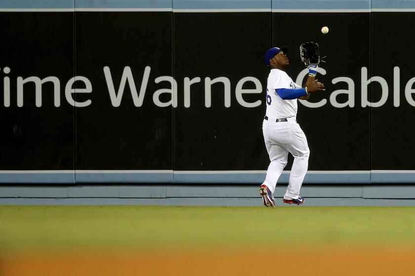 Dodger center fielder Yasiel Puig makes a catch in front of a Time Warner Cable advertisement on the outfield wall during a game against the Angels in 2014 at Dodger Stadium in Los Angeles.