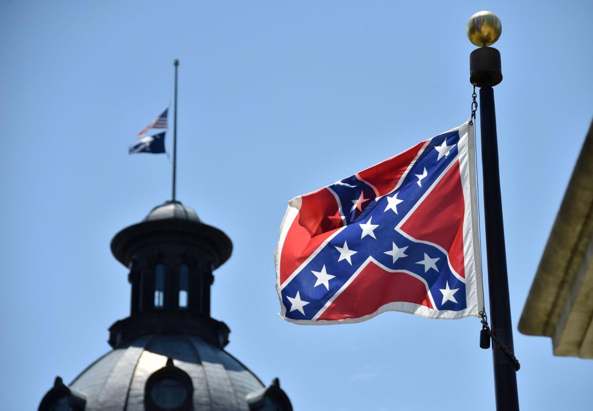 The U.S. and South Carolina flags are seen flying at half-staff behind the Confederate flag, which is erected at a war memorial on the South Carolina Capitol grounds. Controversy over displaying the Confederate flag, which some say is a symbol of white supremacy and hatred, has ensued after the Charleston, S.C., shooting.