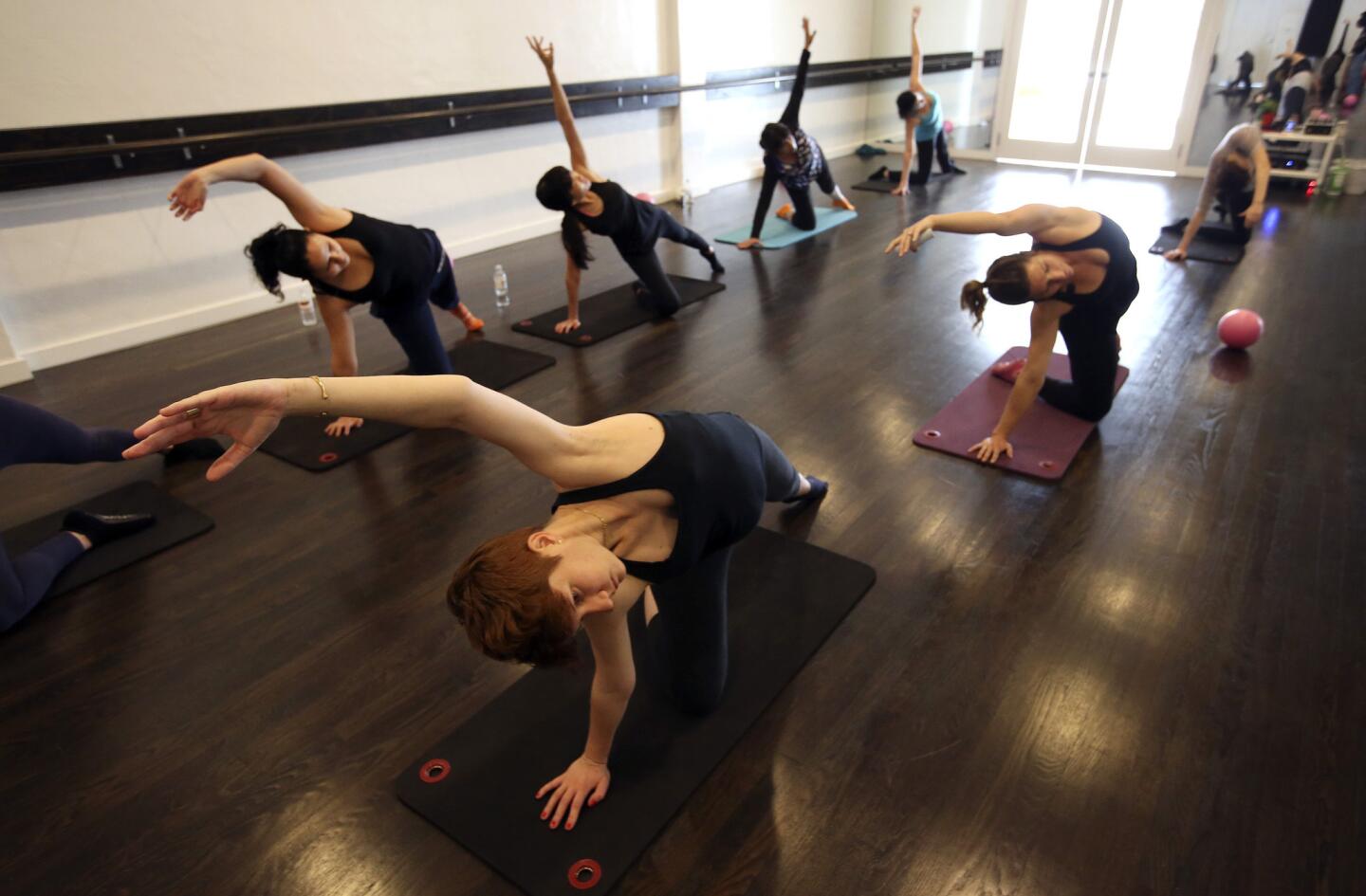 Marie Guillot, foreground, left, does a stretching exercise with others in a ballet barre-based class at Pop Physique in Highland Park.