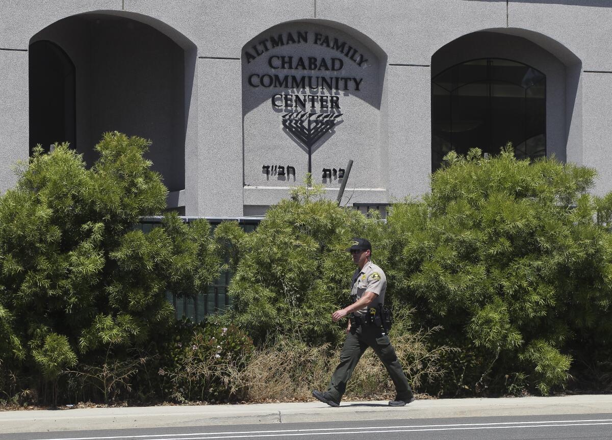 A man in uniform walks past the front of a building that has a sign that includes a menorah.