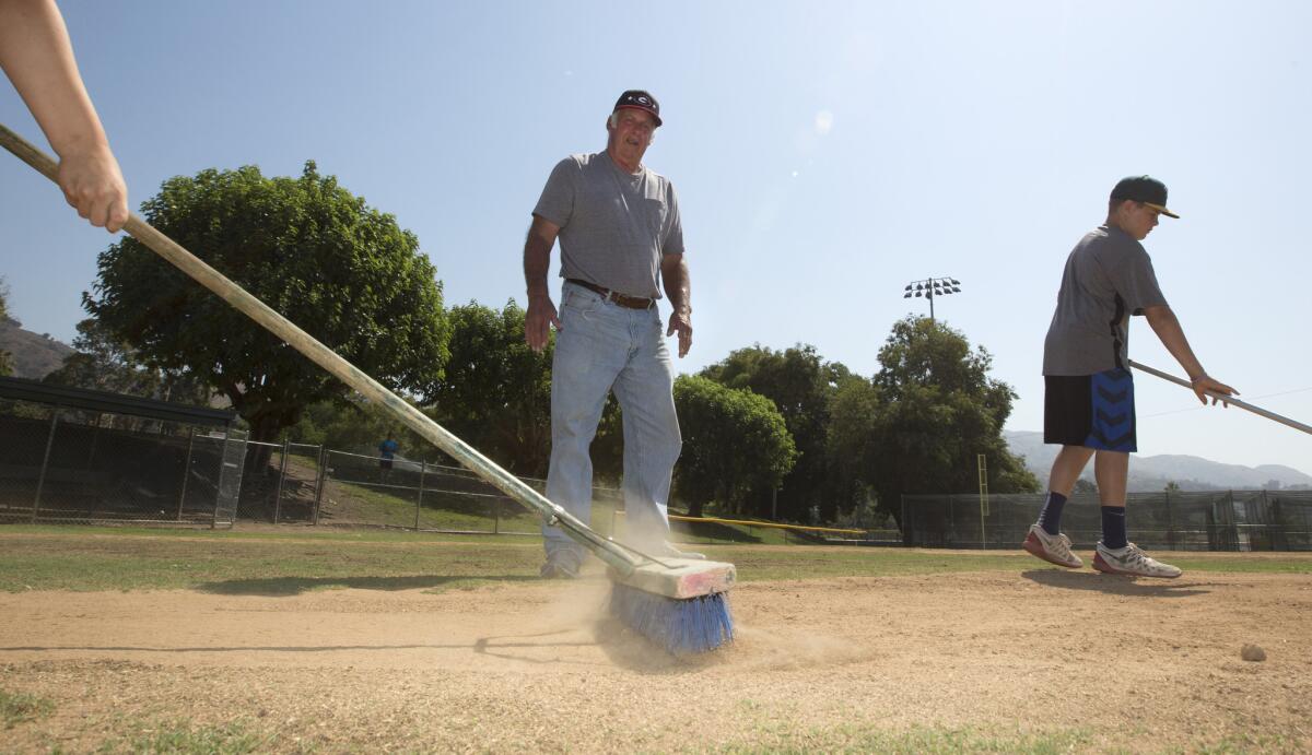 Ted Haller supervises the raking of a mound at the Glendora Little League fields. ( Brian van der Brug / Los Angeles Times)