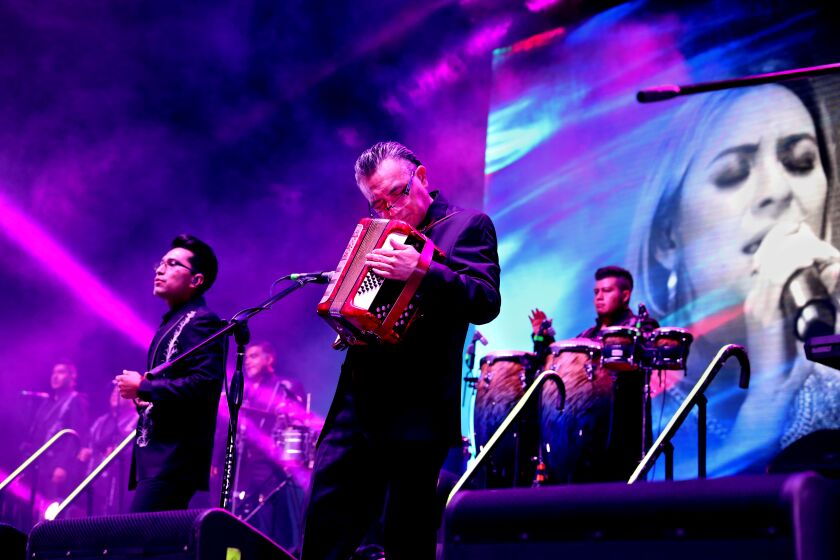 ESTERO, FL - NOVEMBER 07: Jorge Mejia Avante, center, composer/accordion, one of six siblings who make up the core of Los Angeles Azules, shown with Edwin Ordonez, left, and other members, performs during the band's 40 Years anniversary tour at the Hertz Arena on Sunday, Nov. 7, 2021 in Estero, FL. Super cumbia group Los Angeles Azules, of Iztapalapa, a borough of the Federal District of Mexico City, celebrates their 40th anniversary as a band touring the USA. (Gary Coronado / Los Angeles Times)