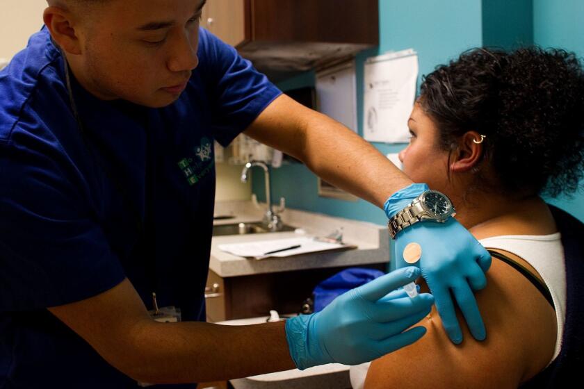 LOS ANGELES, CA - JANUARY 14, 2013: Medical assistant Jesus Cajetero gives Tania Guerrero,31, of Los Angeles a flu shot at T. H. E. Clinic in South Los Angeles on Jan. 14, 2103. California public health officials are bracing for an increase in new flu patients in the coming weeks as the influenza outbreak that has engulfed 47 other states gears up here. (Gina Ferazzi / Los Angeles Times)