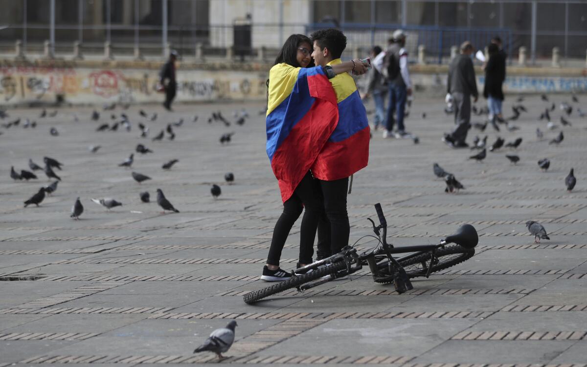 Two people wrapped in a large Colombian flag