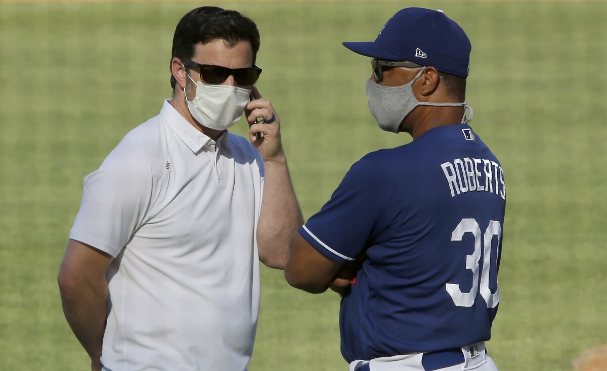 Dodgers general manager Andrew Friedman and manager Dave Roberts talk during practice at Dodger Stadium.