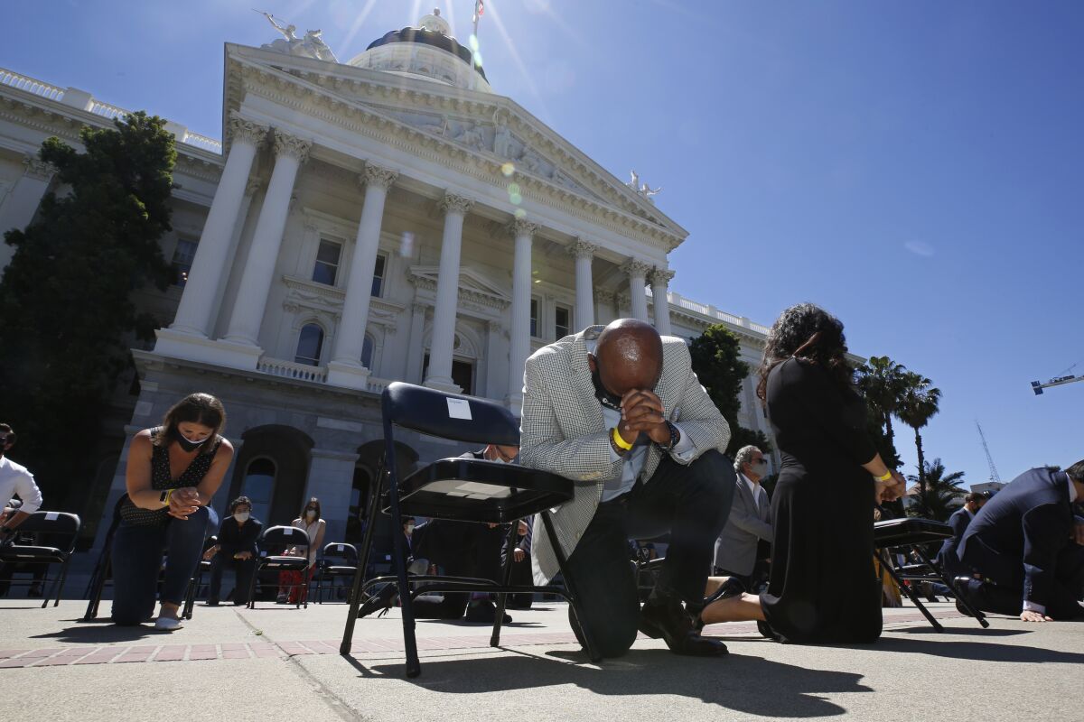 FILE - In this June 9, 2020, file photo, Assemblyman Mike Gipson, D-Carson, bows his head as he and other members of the California Legislature kneel to honor George Floyd at the Capitol in Sacramento, Calif. Lawmakers approved, Thursday, Sept. 9, 2021, Gipson's measure that would prohibit police from using techniques that create a substantial risk of what's known as "positional asphyxia." (AP Photo/Rich Pedroncelli, File)