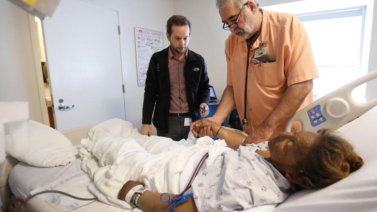 Dr. Jonathan LoPresti, right, a physician at L.A. County-USC Medical Center for 36 years, and resident physician Michael Kendall, left, meet with a patient named Anna who is on dialysis.