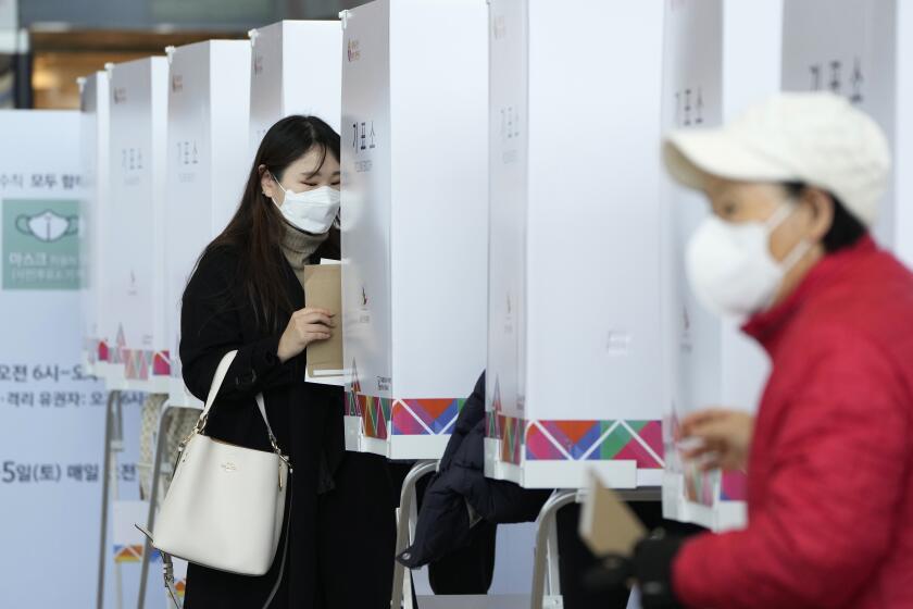 A woman enters a booth to cast vote at a local polling station in Seoul, South Korea