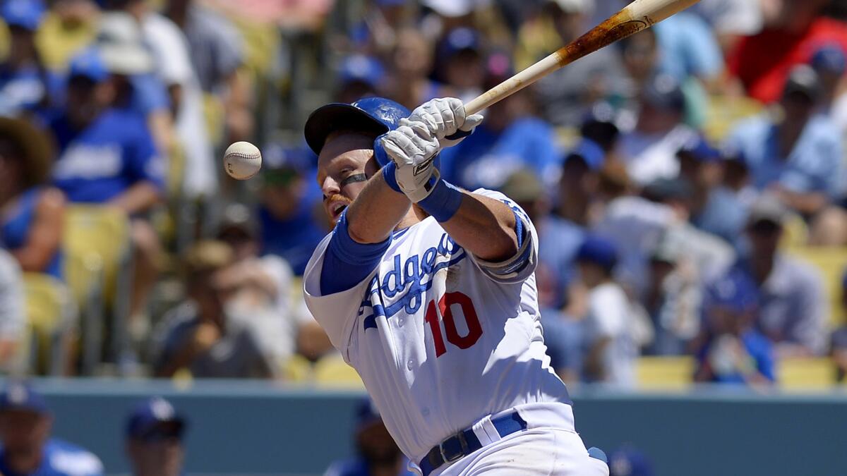 Dodgers third baseman Justin Turner has his helmet knocked off by a foul ball as he bats against the Brewers in the in the fourth inning Sunday at Dodger Stadium.