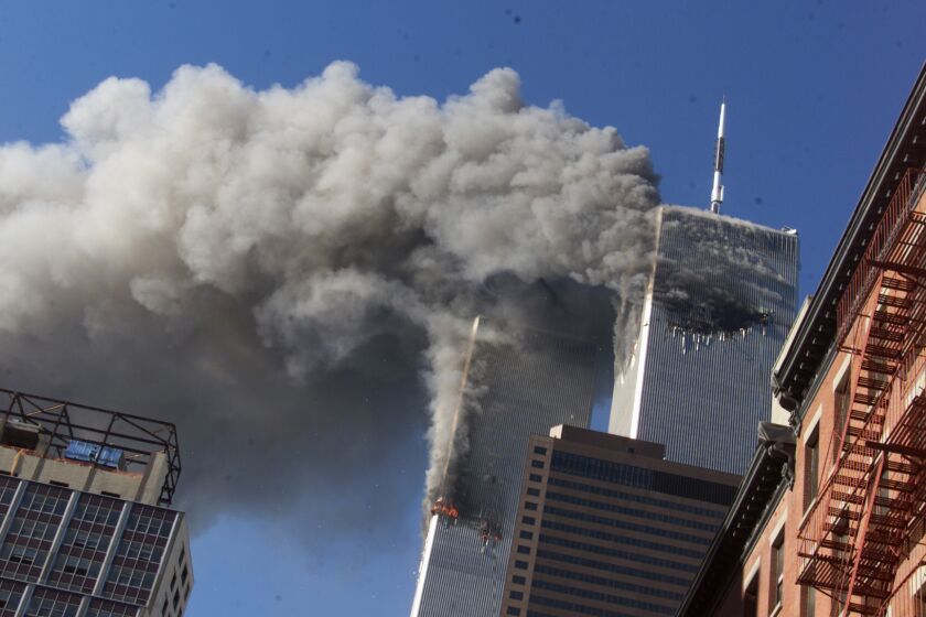 FILE - In this Sept. 11, 2001, file photo, smoke rises from the burning twin towers of the World Trade Center after hijacked planes crashed into the towers, in New York City. The coronavirus pandemic has reshaped how the U.S. is observing the anniversary of 9/11. The terror attacks' 19th anniversary will be marked Friday, Sept. 11, 2020, by dueling ceremonies at the Sept. 11 memorial plaza and a corner nearby in New York. (AP Photo/Richard Drew, File)