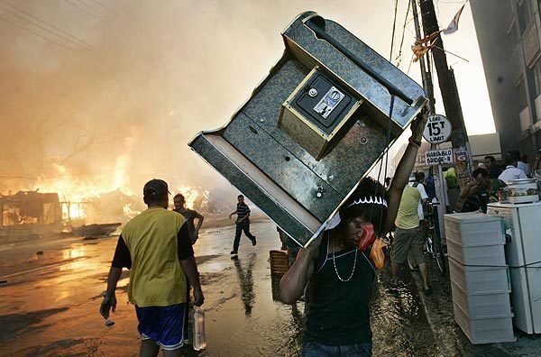 A resident carries a karaoke machine to safety as a fire burns in shanties in Quezon City.