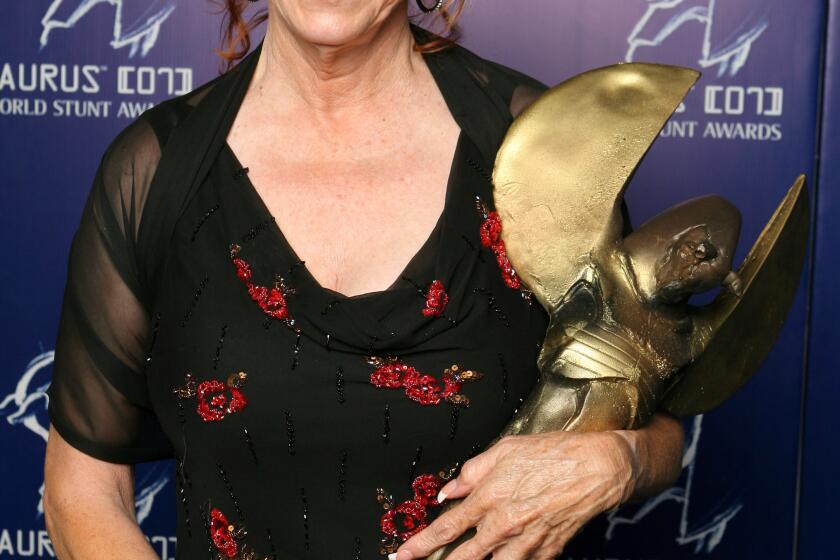 Jeannie Epper hold a large golden trophy with two hands
