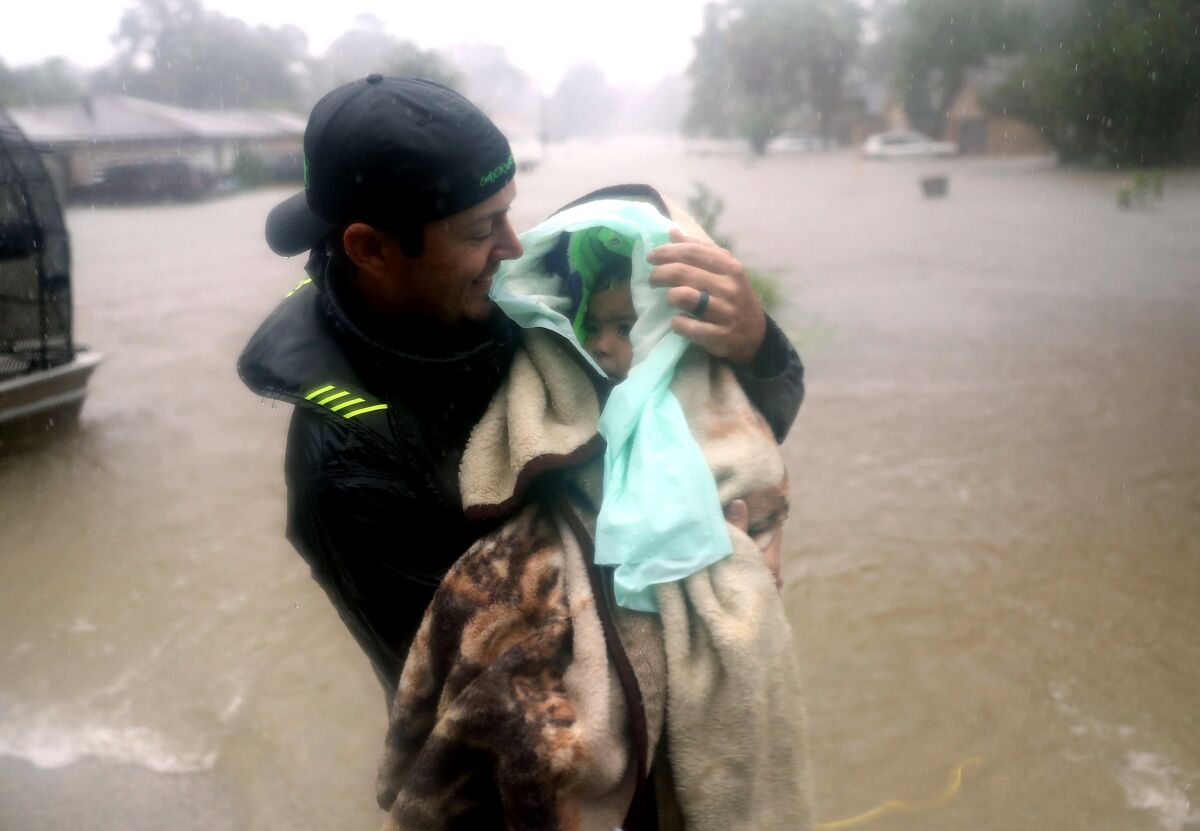 Dean Mize holds a child as he helps evacuate people in Houston. (Joe Raedle / Getty Images)