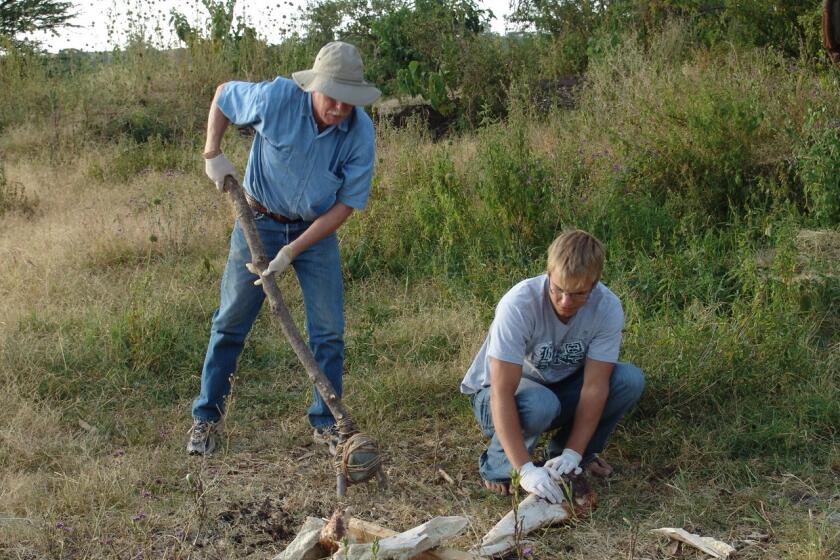 Steve Holen (standing) pictured here with hafted hammer, breaking an elephant femur in Tanzania, Africa in 2006. 
