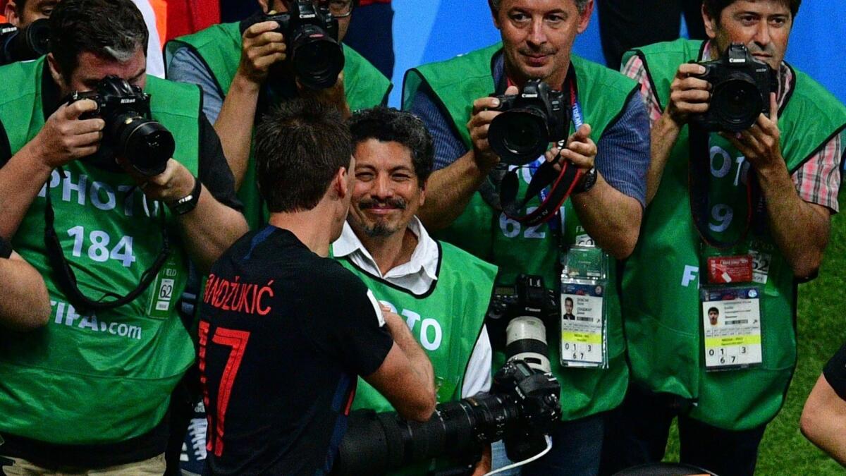 El fotógrafo mexicano de la agencia AFP, Yuri Cortez (c), recibe las disculpas de los jugadores croatas tras quedar debajo en una montaña humana en la celebración de los jugadores croatas.