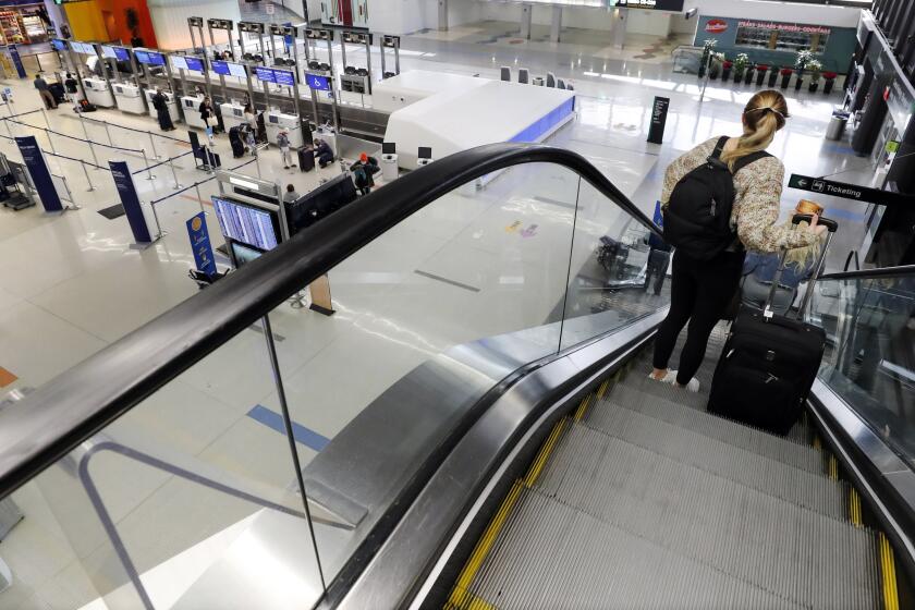 ARCHIVO - Una viajera en una escalera eléctrica con su equipaje tras llegar a la terminal de JetBlue en el Aeropuerto Internacional Logan, el viernes 20 de noviembre de 2020, en Boston. (AP Foto/Michael Dwyer, Archivo)