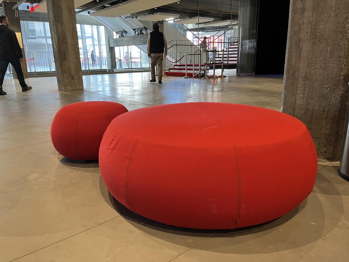 A pair of red poufs for sitting are seen in the concrete lobby of the Academy Museum.
