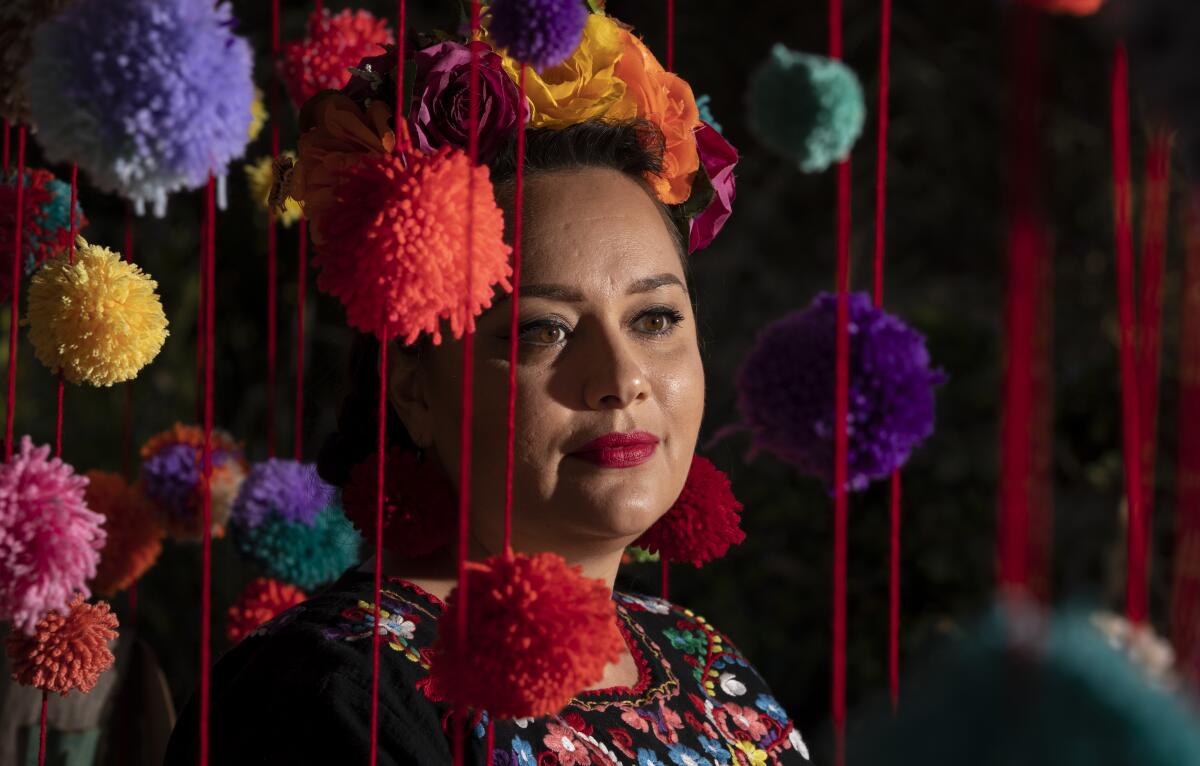 Mixed media artist Katie Ruiz, 37, sits at a "Community Pompom Tree."
