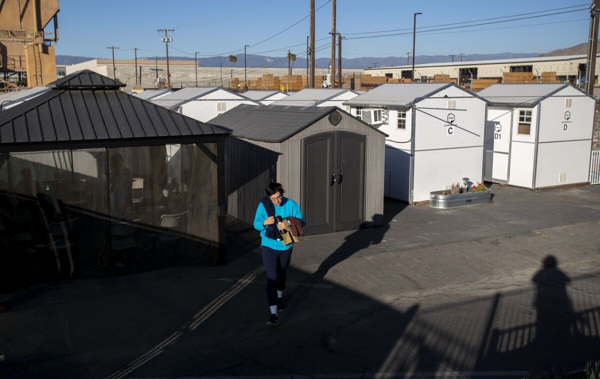 A resident of a tiny home village in Riverside walks to the common shower area