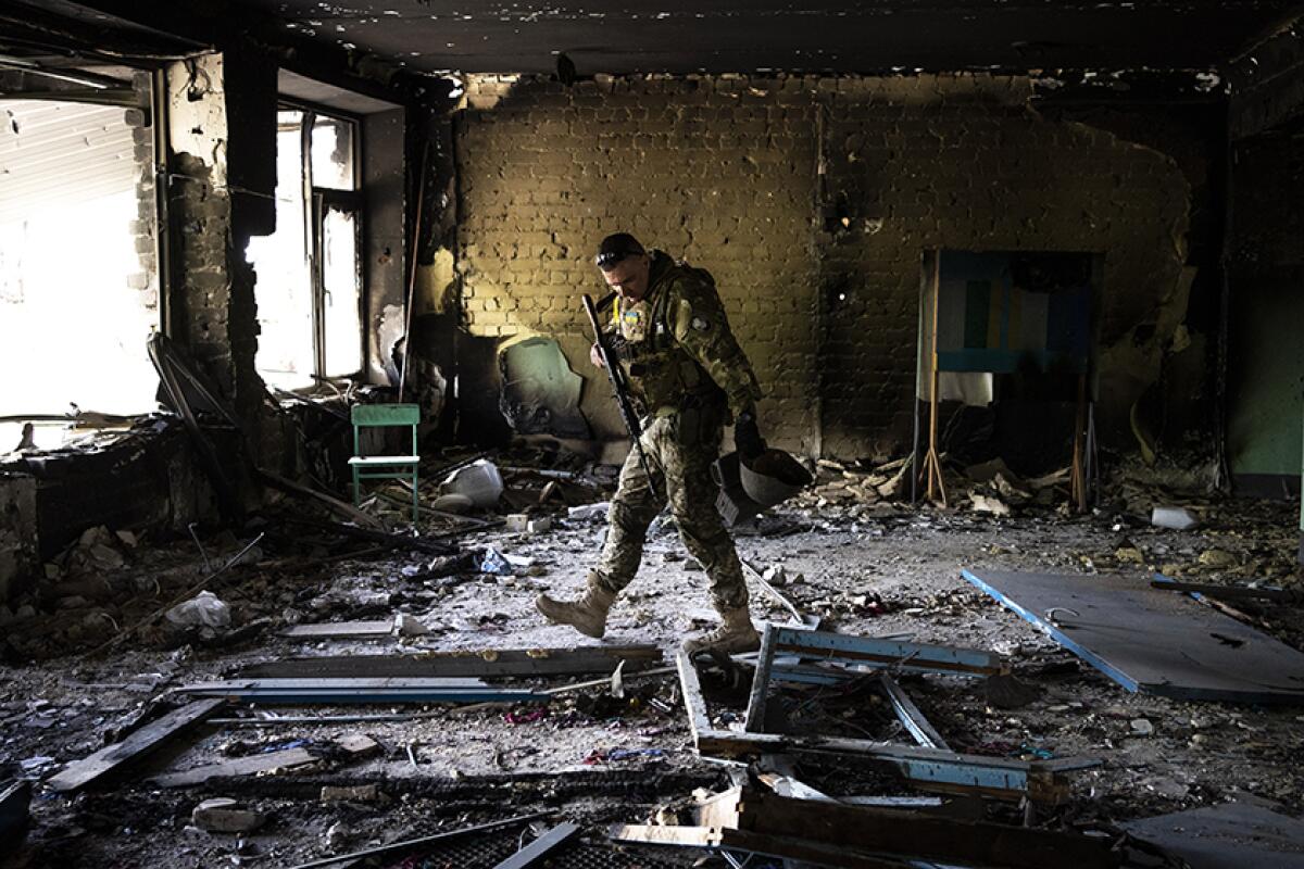 A Ukrainian serviceman inspects a damaged school